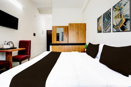 a bedroom with a large white bed and a desk at Hotel O Shivam Grand in Gorakhpur
