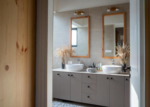 a bathroom with two sinks and two mirrors at Jaadooghar The Chitai Life in Almora