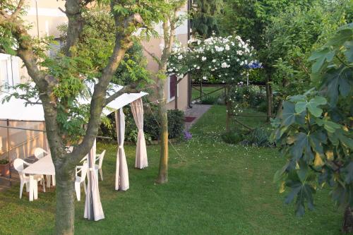 a garden with white tables and chairs and trees at Il Giardino in Trenzano