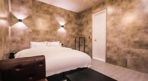 a bedroom with a large white bed and a wall at Hotel Seowa in Gimhae