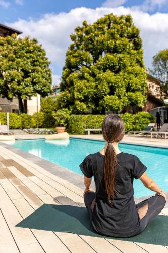 a woman sitting in a yoga pose in front of a pool at Villa Vitali - Bellagio in Bellagio