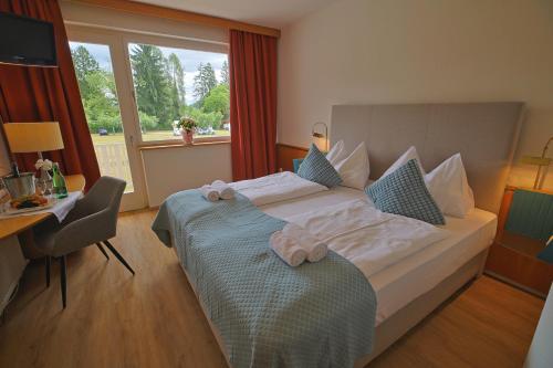 a hotel room with a bed and a desk and a window at Promenaden-Strandhotel Marolt in Sankt Kanzian