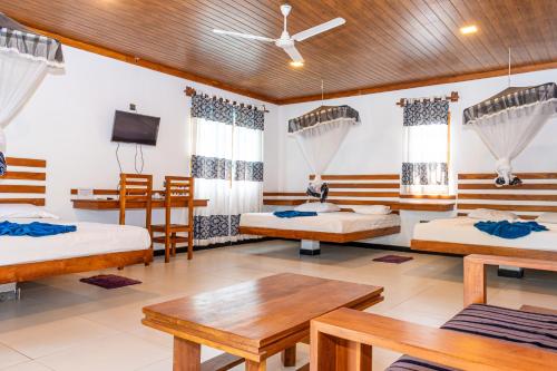 a room with three beds and a tv at Eco Hotel Black & White - Anuradhapura in Mihintale
