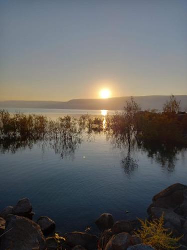 a sunset over a body of water with the sun setting at בקתה 512- אירוח בדרום הגולן in Giv'at Yo'av