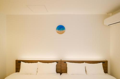 a bed with white pillows and a clock on the wall at MIRATIO Saphir in Onna
