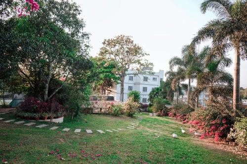 a yard with palm trees and a white building at Nigara Residency in Vandanmedu