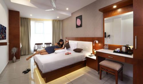 a woman laying on a bed in a hotel room at Nigara Residency in Vandanmedu