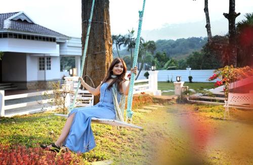 a woman in a blue dress sitting on a swing at Nigara Residency in Vandanmedu