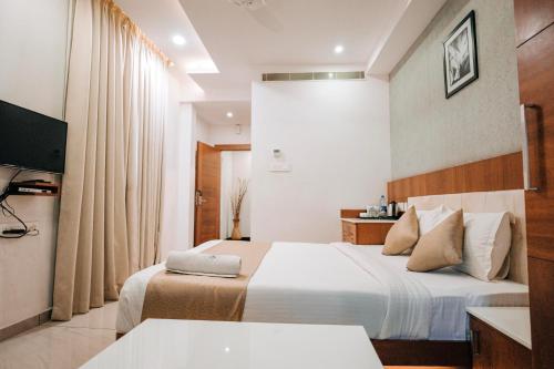 a hotel room with two beds and a television at Nigara Residency in Vandanmedu