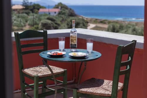 a table with two chairs and a bottle of water and drinks at Dialiskari Villas in Marathopolis