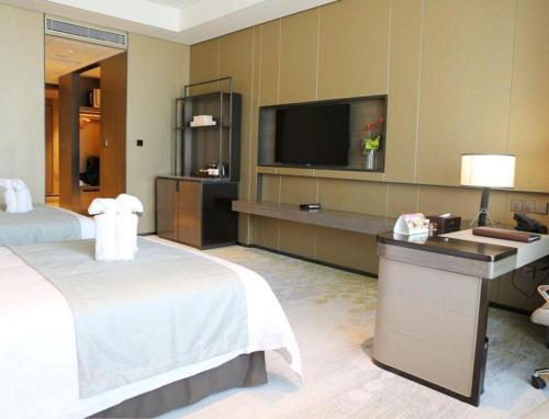 a hotel room with a bed and a flat screen tv at Golden Eagle Summit Hotel Kunshan in Suzhou