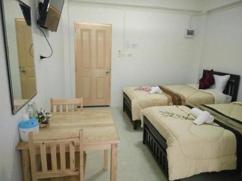 a hotel room with two beds and a table at Rueangrat Hotel in Ranong