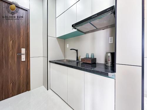 a kitchen with white cabinets and a counter top at Golden Sun Hotel 5 - Quận 2 in Ho Chi Minh City