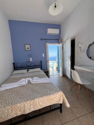 a bedroom with a bed and a blue wall at Stella Nomikou Apartments in Firostefani