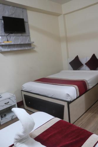 a bedroom with two beds and a tv on the wall at Hotel Kailash Mansarobar Banquet and Restaurant in Kathmandu