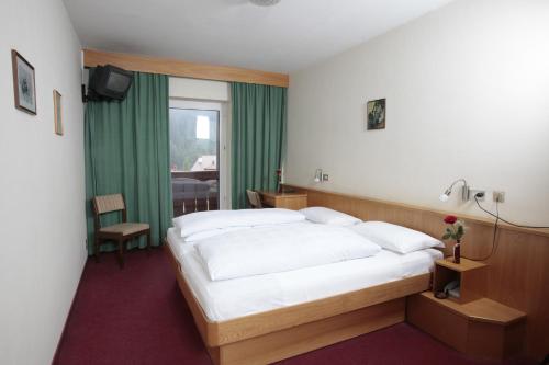 una camera d'albergo con letto e finestra di Hotel Alpino Plan a Selva di Val Gardena