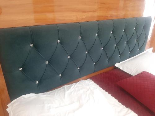 a green headboard of a bed with a red pillow at Parvatiya Homestay in Mussoorie