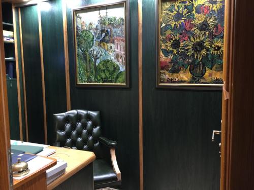 a office with a chair and paintings on the wall at Antik Hotel Sofia in Litomyšl
