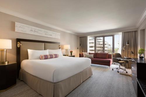 a hotel room with a large bed and a desk at The Fairmont Washington DC in Washington, D.C.