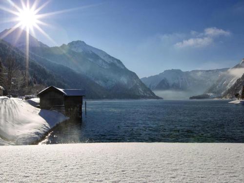 a view of a body of water with the sun shining at Apartment in Achenkirch with a garden in Achensee