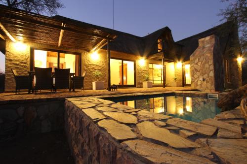 a house with a swimming pool at night at Giraffe Lodge in Hoedspruit