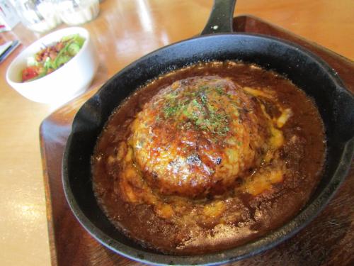 a chicken in a pan with sauce on a table at Guesthouse ＆ Beach Cafe Fuego in Hyuga