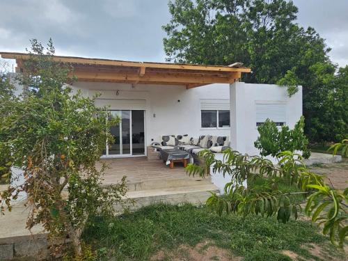 a white house with a wooden deck with chairs at Casa de Mima, Casa Rural in Restinga Smir