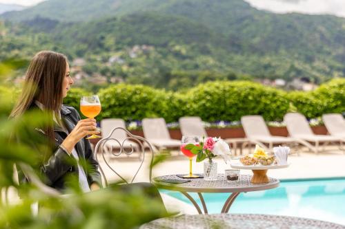 a woman sitting at a table with a glass of wine at Villa Vitali - Bellagio in Bellagio