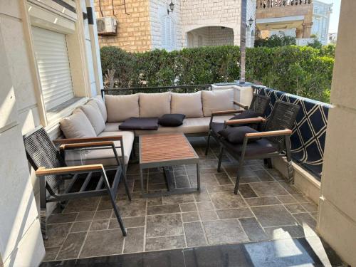 a patio with a couch and chairs on a balcony at فيلا بمسبح خاص وتشطيب فاخر قرب البحيرة in El Alamein