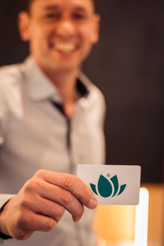 a man holding a cup with a logo on it at Hotel Villa Flora in Velden am Wörthersee