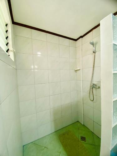 a bathroom with a shower with white tiles at TipTop Hotel, Resto and Delishop in Panglao