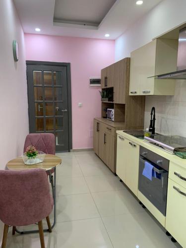 a kitchen with pink walls and a table and chairs at Marie in Grand-Bassam