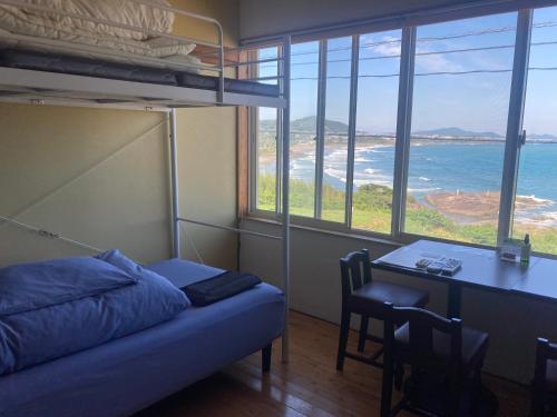 a bedroom with a bed and a desk with a table at Guesthouse ＆ Beach Cafe Fuego in Hyuga