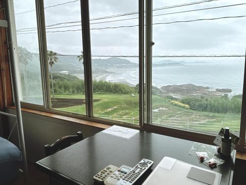 two remote controls sitting on a table in front of a window at Guesthouse ＆ Beach Cafe Fuego in Hyuga