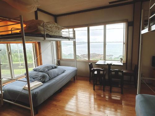 a bedroom with a bunk bed and a desk with a table at Guesthouse ＆ Beach Cafe Fuego in Hyuga