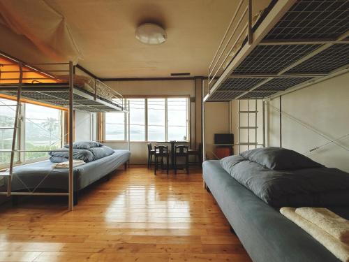 a bedroom with two bunk beds and a table at Guesthouse ＆ Beach Cafe Fuego in Hyuga