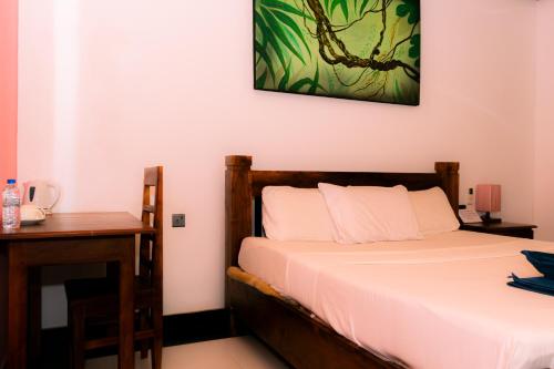 a bedroom with a bed and a desk with a bed sidx sidx sidx at Eco Hotel Black & White - Anuradhapura in Mihintale