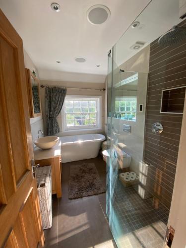 a bathroom with a tub and a shower and a sink at Four bedroom Rural home in the South Downs in Linchmere