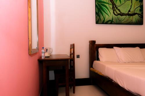 a bedroom with a bed and a table with a mirror at Eco Hotel Black & White - Anuradhapura in Mihintale