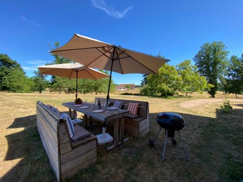 a table with an umbrella and two chairs and a grill at Grand Gîte chez Domaine Château de Bussolles in Barrais-Bussolles