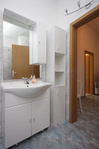 a white bathroom with a sink and a mirror at Apartment GRANDE in Preko