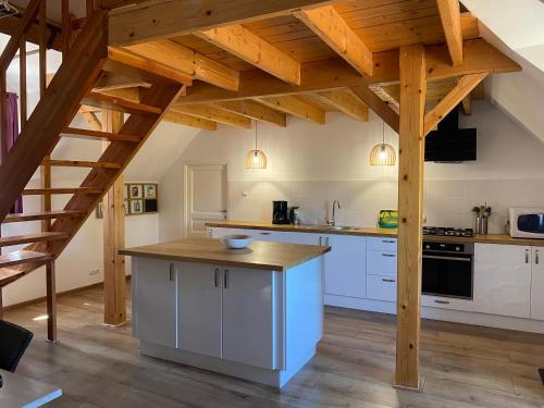 an attic kitchen with white cabinets and wooden beams at Grand Gîte chez Domaine Château de Bussolles in Barrais-Bussolles