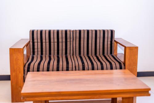 a wooden chair with a wooden bench in a room at Eco Hotel Black & White - Anuradhapura in Mihintale