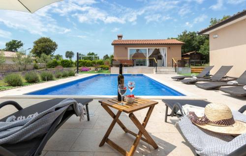 a patio with a table with a bottle of wine next to a pool at Beautiful Home In Kunj With Wifi in Kunj