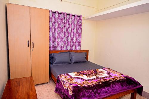 a bedroom with a bed with a purple bedspread at Coorg mansion in Madikeri