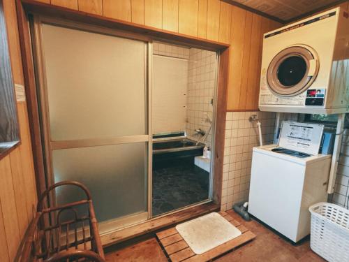 a kitchen with a refrigerator and a microwave at Guesthouse ＆ Beach Cafe Fuego in Hyuga