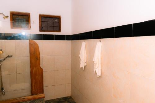 a bathroom with a shower and towels hanging on the wall at Eco Hotel Black & White - Anuradhapura in Mihintale