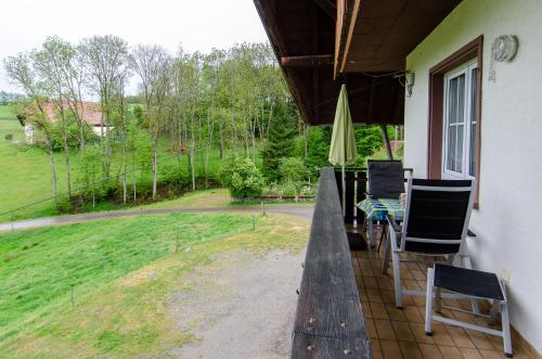 a porch with chairs and a table and an umbrella at Heizmannshof in Hofstetten