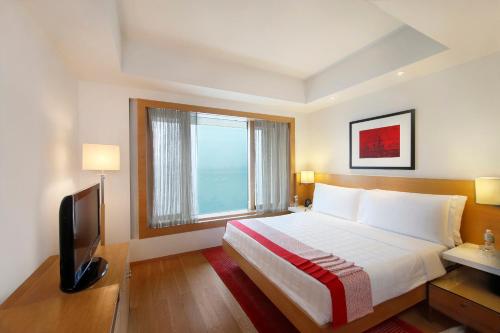 a bedroom with a bed and a tv and a window at Trident Nariman Point in Mumbai
