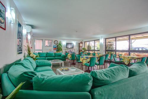 uma grande sala de estar com sofás verdes e mesas em Hotel Diamante em Rimini